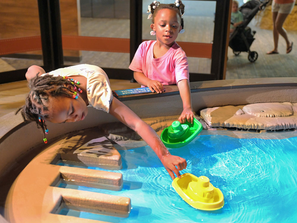 Two children playing with plastic boats in the ScienceWorks Water Table.